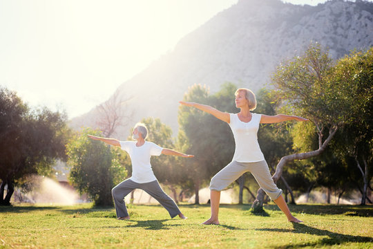 Yoga at park. Senior family couple exercising outdoors. Concept of healthy lifestyle.