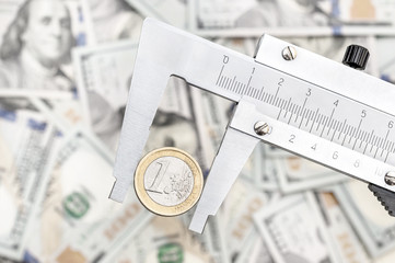 Vernier caliper with coin of one euro over background of dollar bills. Exchange rate by euro to...