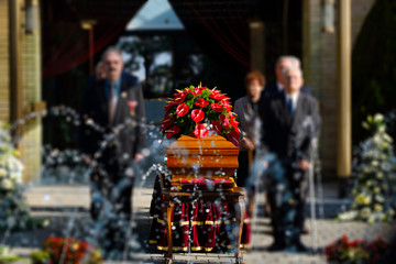 Naklejka premium Blurred image of family standing by a coffin at a funeral