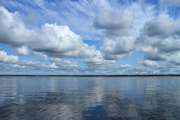 Naklejka na ściany i meble beautiful seascape calm, cumulus clouds reflected in sea water panorama
