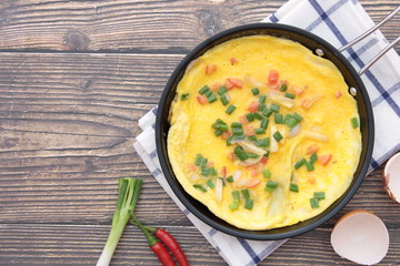 Omelette in a pan that is placed on a wooden background
