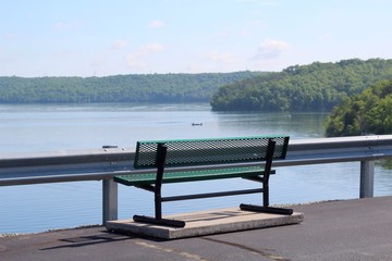 A empty metal bench on the path with a view of the lake.