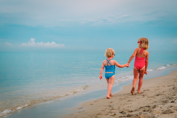 Naklejka premium cute little girls go swim on beach vacation
