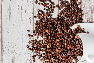 Black coffee in white cup and coffee beans on light wooden background. Top view, space for text