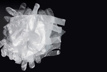 Plastic bag with handles, gloves, on a black background . Used plastic bag for recycling. Concept - ecology, planet pollution with plastic cellophane polyethylene