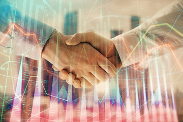 Fototapeta na wymiar Double exposure of financial graph on cityscape background with two businessman handshake. Concept of stock market deal