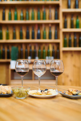 Three wineglasses and snack for sommelier on wooden table