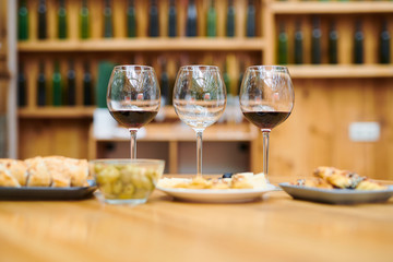 Row of wineglasses with red wine and snacks near by prepared for sommelier