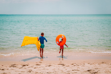 Obraz premium happy boy and girl with floaties run swim on beach