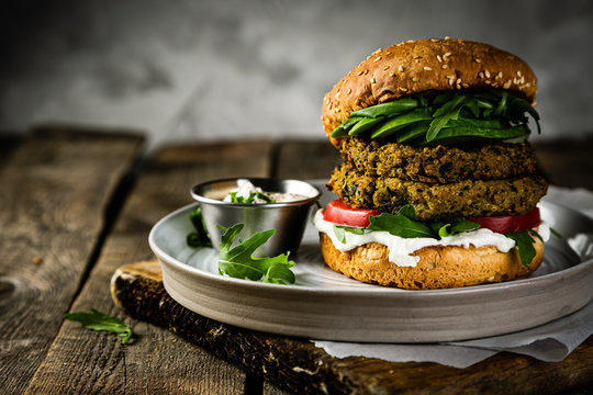 Vegan zucchini burger and ingredients on rustic wood background, copy space