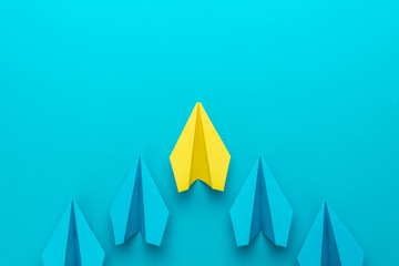 Top view of yellow plane leading blue ones. Leadership concept with paper planes over turquoise blue background with copy space. Flat lay image of business competition concept.
