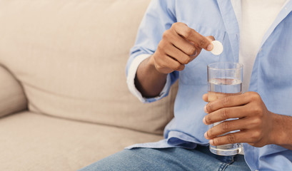 Man holding soluble white pill and a glass of water