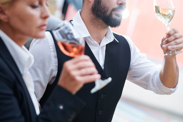 Bearded sommelier with glass of white wine checking its quality