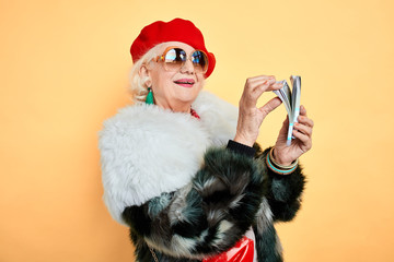 grandmother rejoicing at earned money, holiday, success, happiness concept. isolated yellow...