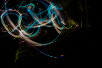 Long exposure photography made with light paint of various colors on neutral black background, waves, curves and swirls, curvilinear or rounded pattern.