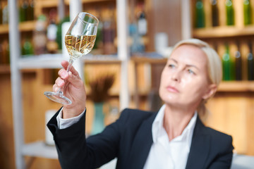 Female hand holding bokal woth white wine while examining its color