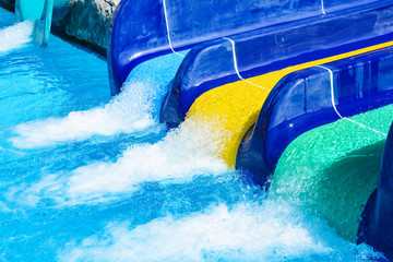 Multi-colored water slides with water jets in the blue pool