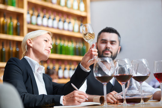 Serious professional sommeliers examining color of white wine in bokal