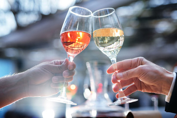 Two humans clinking with wineglasses with brandy or wine
