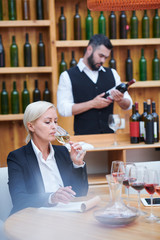 Pretty winery expert degustating white wine from wineglass