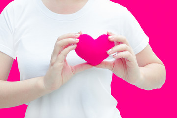 Woman hand holding plush a red heart at left her chest on pink background ,Valentine day concept ,Love heart, protect and healthcare