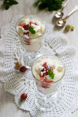 Eton mess, traditional English dessert with gooseberry, whipped cream and meringue on a light background. Rustic style.