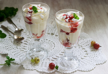 Eton mess, traditional English dessert with gooseberry, whipped cream and meringue on a light background. Rustic style.