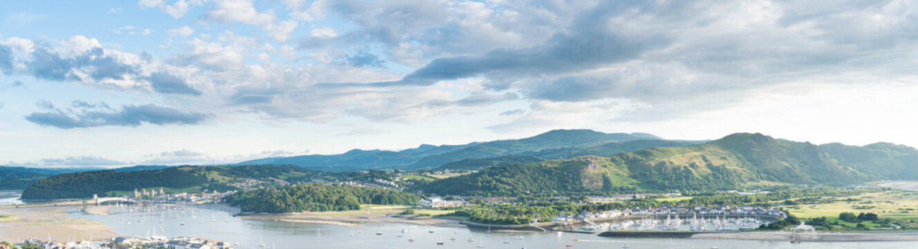 Panoramic North Wales vista over the Conwy estuary nestled below the Welsh mountains. Conwy castle and marina bathed in beautiful evening light.