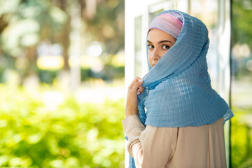 Young attractive Arabian woman in hijab looking at you over her shoulder