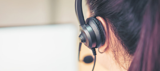 Back view of woman consultant wearing microphone headset of customer support phone operator at...