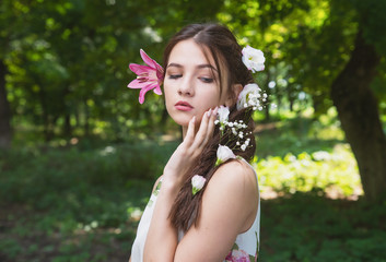 Naklejka premium beautiful girl with lilies in her hair, flowers in the luxurious dark hair of a young lady