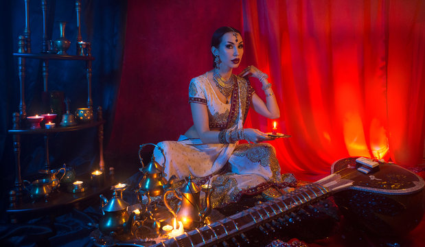 Beautiful young indian woman in traditional Sari clothing and Oriental Jewelry with candle