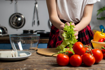 girl prepares a vegetarian salad, she adds sliced greens to an empty plate, cooking healthy food, close-up