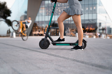 Unrecognizable woman, on e scooter in city environment 