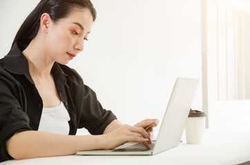 Young woman holding credit card and using laptop computer. Online shopping concept.