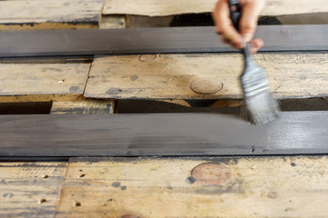 Painting boards with a brush held in hand. Gray, anthracite wood paint.