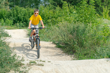 A boy rides a bicycle on a hilly road cycle track