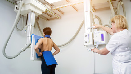 Radiologist and patient in a x-ray room. Classic ceiling-mounted x-ray system.