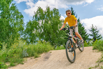 Fototapeta na wymiar A boy on a bike down the hill on a forest road