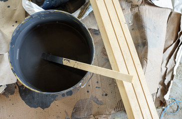 Mixing paint in a bucket with a wooden stick