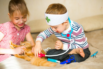 little boy in the glasses with syndrome dawn and blonde girl play with toys and ginger cat