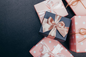 beautiful gift boxes wrapped in paper with red, gold and pink ribbon on a black surface. Top view...