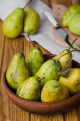 fresh ripe pears in a clay bowl on a dark wooden background. Rustic style