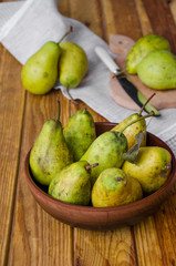 fresh ripe pears in a clay bowl on a dark wooden background. Rustic style