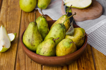 fresh ripe pears in a clay bowl on a dark wooden background. Rustic style