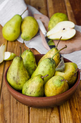 fresh ripe pears in a clay bowl on a dark wooden background. Rustic style