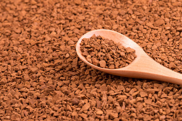 Instant coffee in a spoon close-up. Instant granulated coffee and wooden spoon.