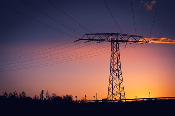 Fototapeta premium Electricity pylon silhouetted against a sunset
