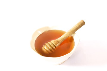 honey and wooden scoop in cup on white background