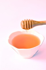 honey on wooden scoop drop to cup in white background